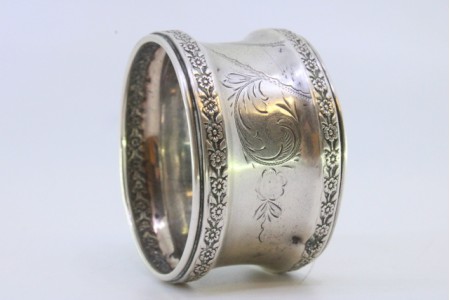 Argola de guardanapo em prata com motivos florais gravados envolvendo cartela para monograma.